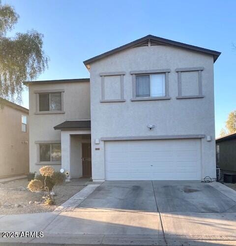 traditional home featuring concrete driveway, an attached garage, and stucco siding