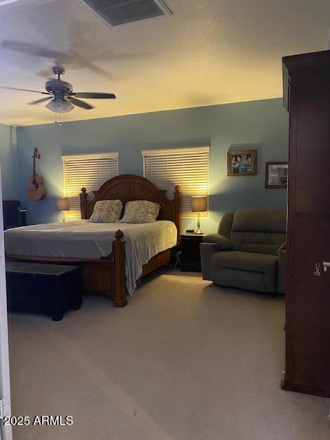 carpeted bedroom featuring a ceiling fan and visible vents