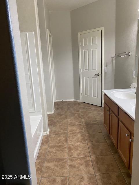 full bath featuring tile patterned flooring, vanity, baseboards, and a bath