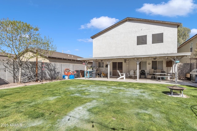 rear view of property featuring a yard, an outdoor fire pit, a patio, and a fenced backyard