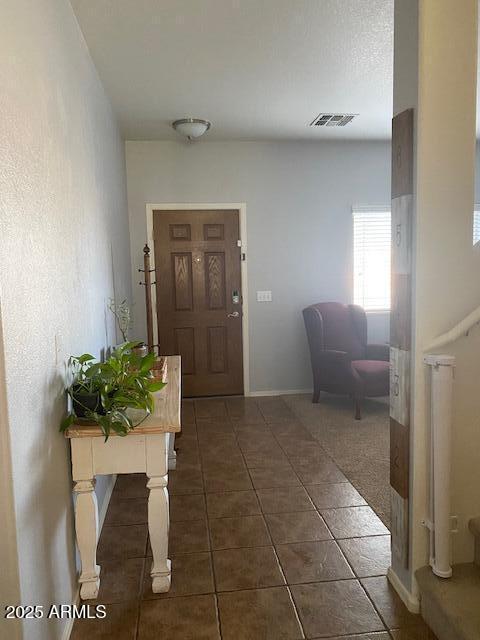 foyer entrance with visible vents, dark tile patterned floors, and baseboards