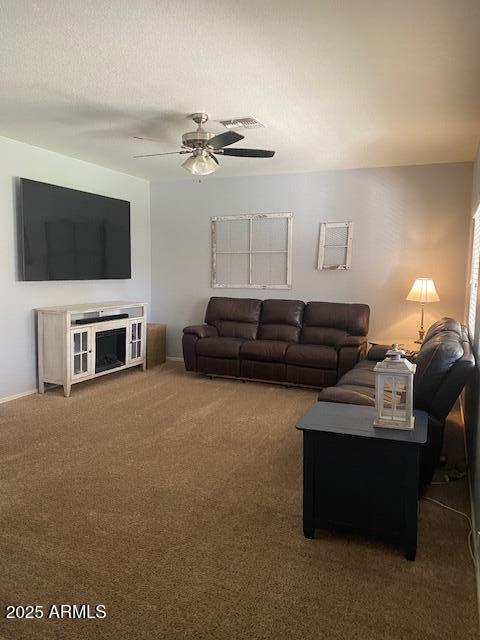 living room with a ceiling fan, visible vents, carpet floors, and a textured ceiling