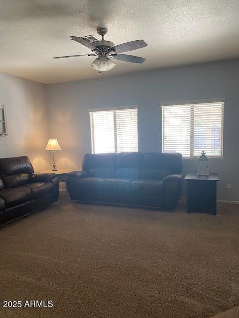 living area with a textured ceiling, ceiling fan, and carpet