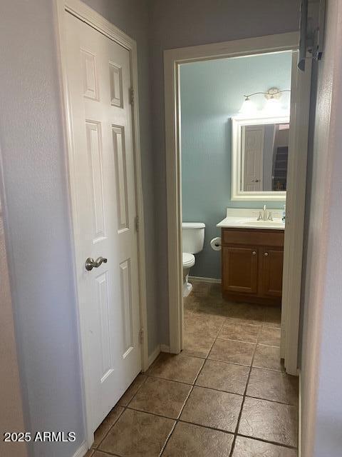 half bath featuring toilet, tile patterned flooring, baseboards, and vanity