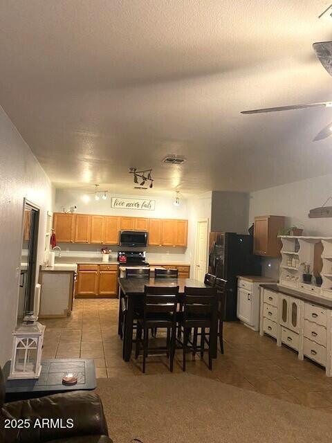 dining area with a ceiling fan, visible vents, a textured ceiling, and light tile patterned floors