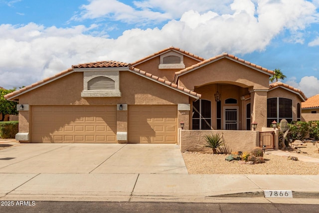 mediterranean / spanish home featuring an attached garage, driveway, fence, and stucco siding