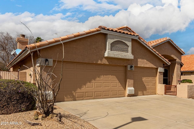 view of front of property with concrete driveway, a tiled roof, an attached garage, fence, and stucco siding