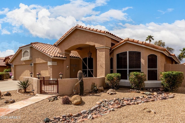 mediterranean / spanish home with an attached garage, fence, concrete driveway, a gate, and stucco siding