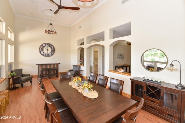 dining space featuring light hardwood / wood-style flooring, a high ceiling, ceiling fan, and crown molding