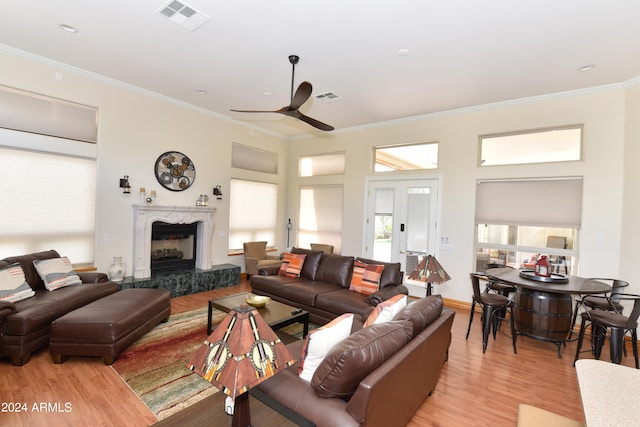 living room featuring hardwood / wood-style flooring, ornamental molding, a high end fireplace, and ceiling fan