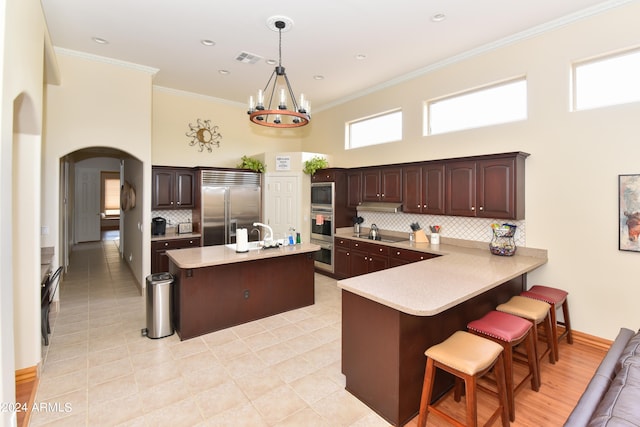 kitchen with built in appliances, decorative backsplash, and a high ceiling