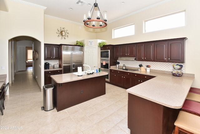 kitchen with built in appliances, decorative backsplash, light tile patterned floors, and a towering ceiling