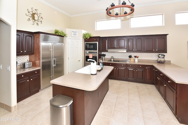 kitchen with backsplash, a healthy amount of sunlight, and built in appliances