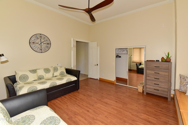 living room with ceiling fan, crown molding, hardwood / wood-style flooring, and a towering ceiling