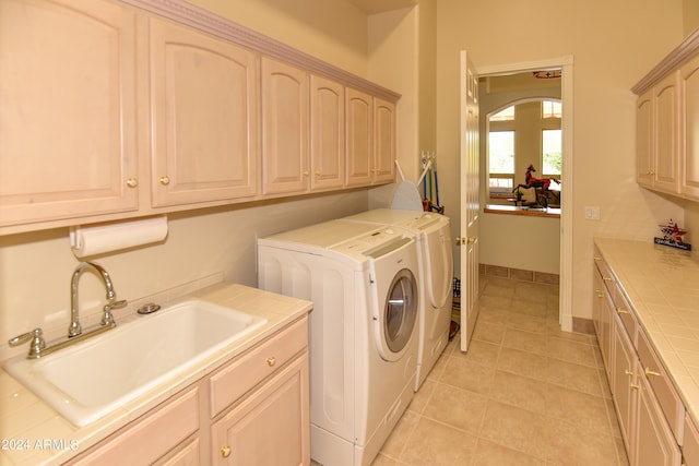 clothes washing area featuring washer and clothes dryer, sink, cabinets, and light tile patterned floors