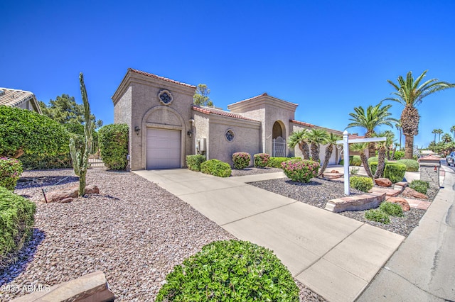 mediterranean / spanish home with driveway, a tile roof, an attached garage, and stucco siding