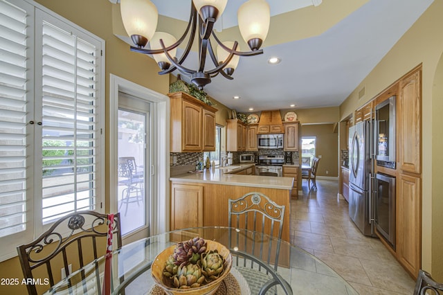 kitchen featuring appliances with stainless steel finishes, backsplash, a peninsula, beverage cooler, and a sink