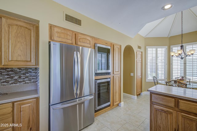kitchen featuring freestanding refrigerator, beverage cooler, decorative backsplash, arched walkways, and lofted ceiling