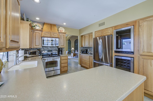 kitchen featuring appliances with stainless steel finishes, a sink, wine cooler, arched walkways, and decorative backsplash