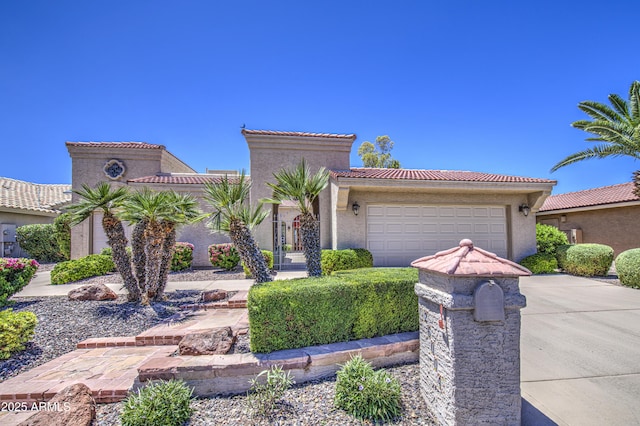 mediterranean / spanish-style home with driveway, a tile roof, a garage, and stucco siding