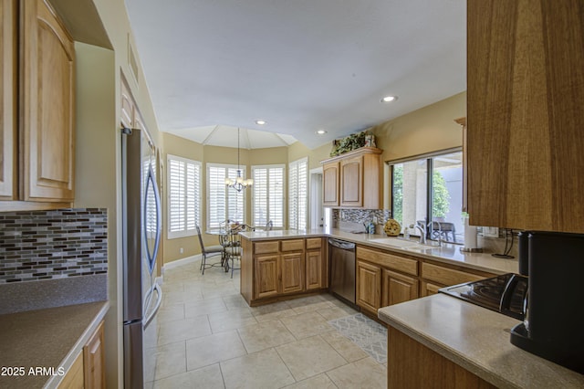 kitchen with stainless steel appliances, a sink, a chandelier, a peninsula, and tasteful backsplash