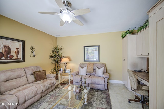 living room with a ceiling fan, light tile patterned floors, a desk, and baseboards