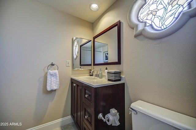 bathroom with toilet, vanity, and tile patterned flooring