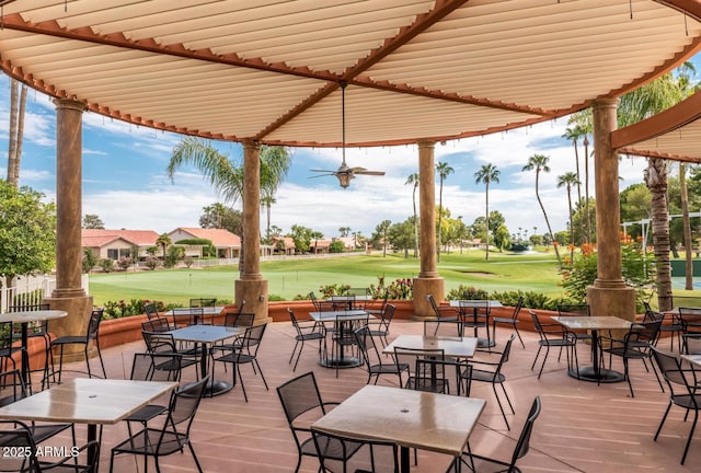view of patio with view of golf course, an area to practice putting, and outdoor dining space
