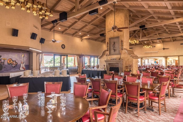 dining area with high vaulted ceiling, wood ceiling, ceiling fan, beam ceiling, and a fireplace