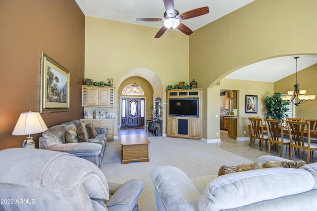 living area with arched walkways, high vaulted ceiling, a chandelier, ceiling fan, and baseboards