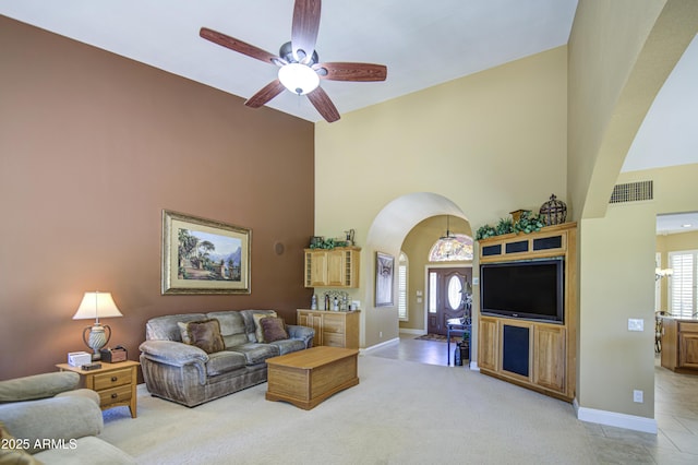living area featuring arched walkways, high vaulted ceiling, healthy amount of natural light, a ceiling fan, and baseboards