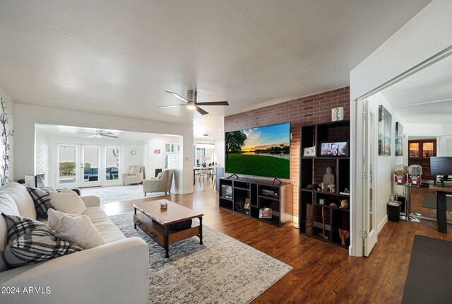 living room featuring ceiling fan, wood-type flooring, brick wall, and french doors