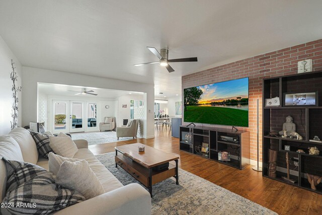 living room featuring ceiling fan, brick wall, and wood-type flooring