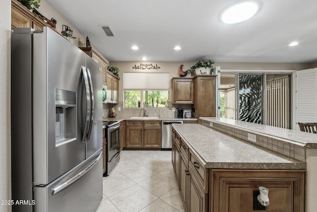 kitchen featuring backsplash, visible vents, a center island, a sink, and stainless steel appliances