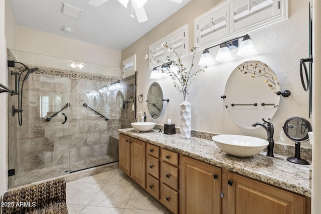 bathroom with ceiling fan, visible vents, a sink, and a stall shower