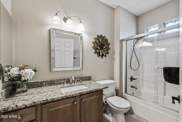 full bathroom featuring vanity, tile patterned floors, toilet, shower / bath combination with glass door, and a textured wall