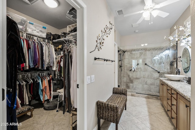full bathroom featuring a walk in closet, vanity, tiled shower, and visible vents