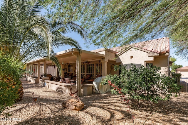 rear view of house with fence, stucco siding, a ceiling fan, a patio area, and a tiled roof