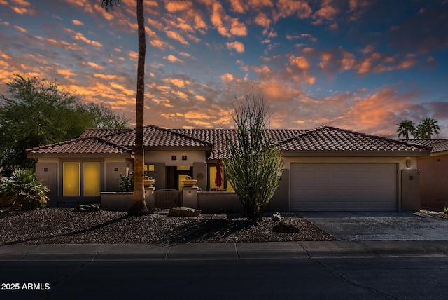 mediterranean / spanish house with a garage, stucco siding, concrete driveway, and a tiled roof