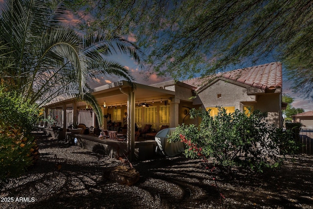 back of property featuring fence, a tile roof, stucco siding, a patio area, and a ceiling fan