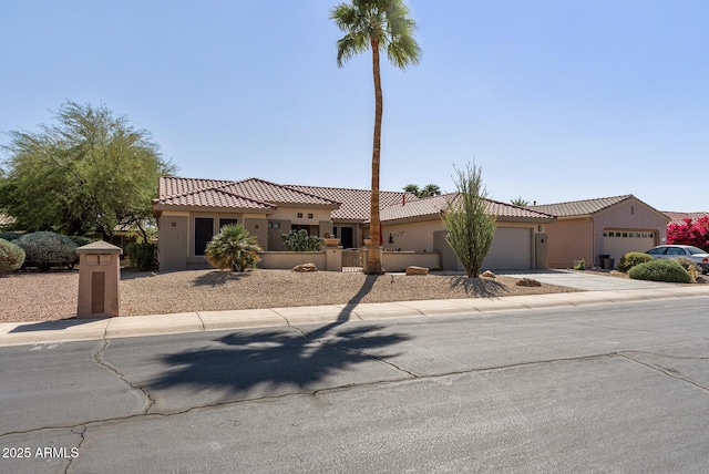mediterranean / spanish house with a garage, stucco siding, driveway, and a tile roof