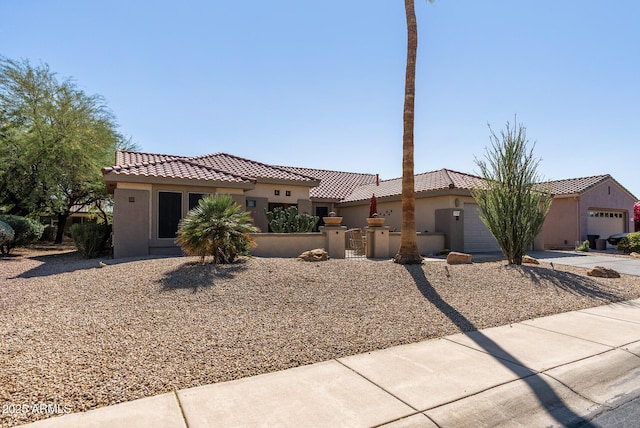 mediterranean / spanish house featuring a tiled roof, driveway, a fenced front yard, and stucco siding