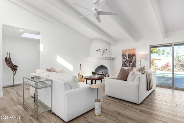 living room with a fireplace, lofted ceiling with beams, light hardwood / wood-style flooring, and ceiling fan