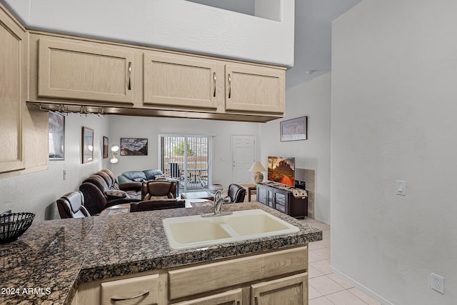 kitchen with dark stone countertops, sink, light tile patterned flooring, and light brown cabinets