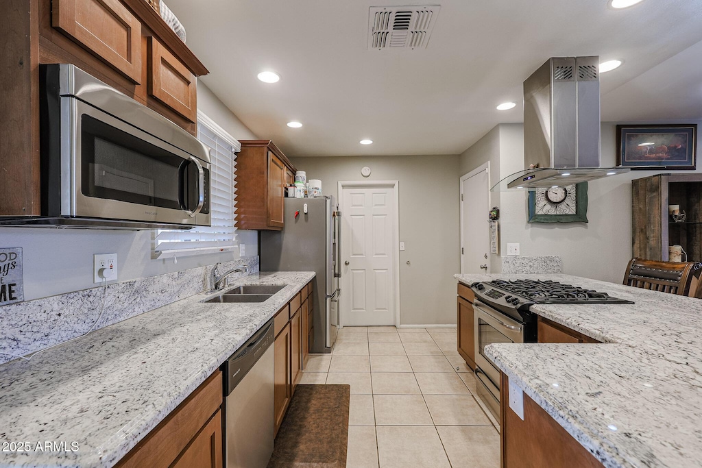 kitchen with light stone countertops, appliances with stainless steel finishes, island exhaust hood, sink, and light tile patterned floors