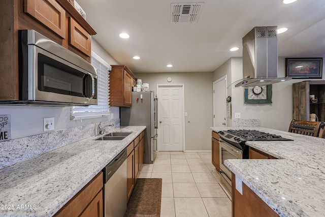 kitchen with light stone countertops, appliances with stainless steel finishes, island exhaust hood, sink, and light tile patterned floors