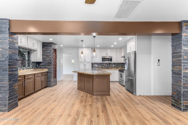 kitchen with white cabinets, appliances with stainless steel finishes, light stone countertops, and light hardwood / wood-style flooring