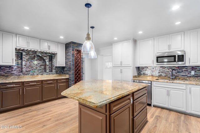 kitchen featuring a kitchen island, light hardwood / wood-style floors, stainless steel appliances, sink, and white cabinetry