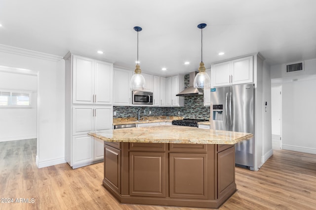 kitchen with appliances with stainless steel finishes, a kitchen island, hanging light fixtures, and white cabinetry