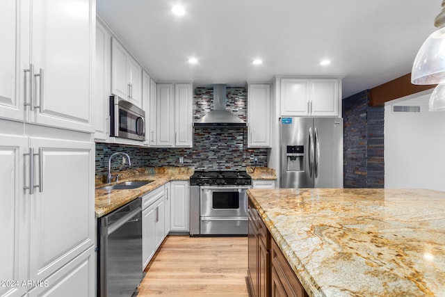 kitchen with white cabinets, appliances with stainless steel finishes, and wall chimney exhaust hood